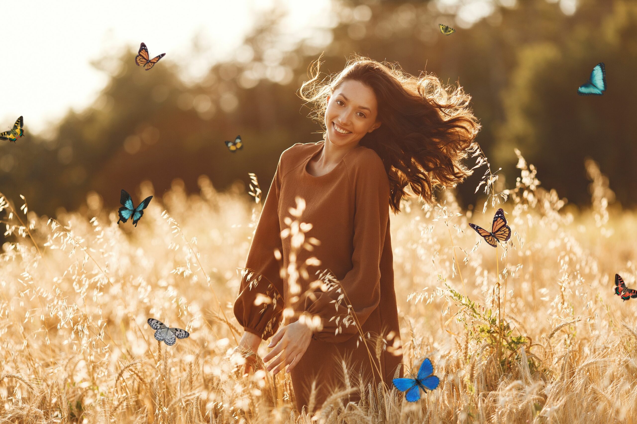 Smiling woman in a field surrounded by colorful butterflies wondering what do butterflies symbolize